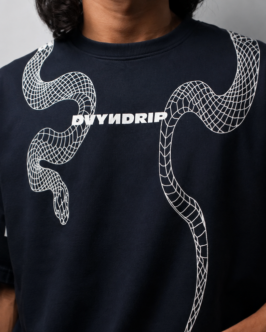 A close-up of a person wearing a navy blue t-shirt with a white wireframe snake graphic and the brand name 'DVYNDRIP' printed across the chest.