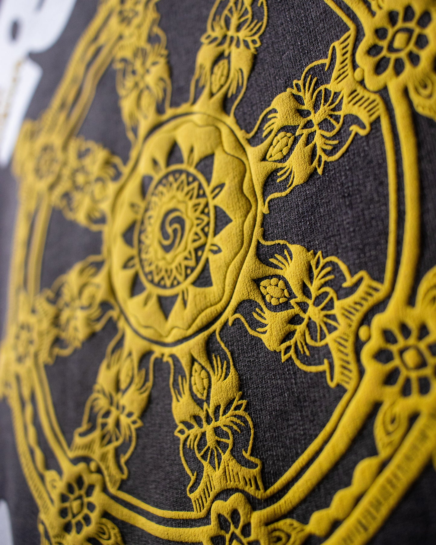 Close-up of the gold wheel print on the back of the DVYNDRIP Preserver T-shirt showing detailed ink texture