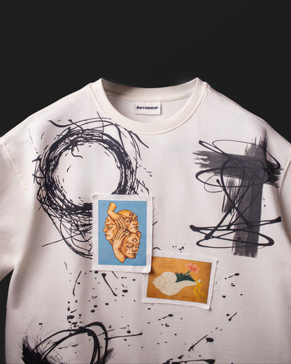 Front chest detail of the DVYNDRIP Creator T-shirt with abstract brush graphics and stitched artwork patches