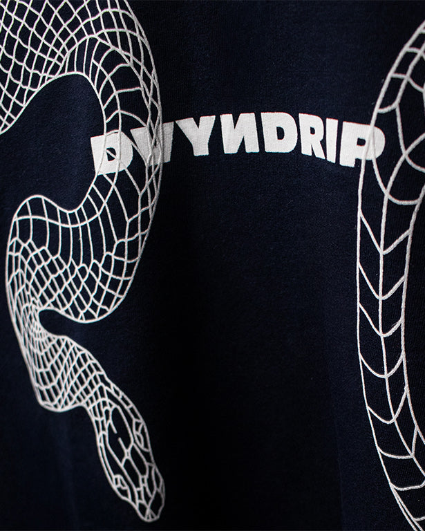 Close-up of the DVYNDRIP Destroyer T-shirt front graphic featuring a white abstract serpent-style line design surrounding the DVYNDRIP logo on navy fabric