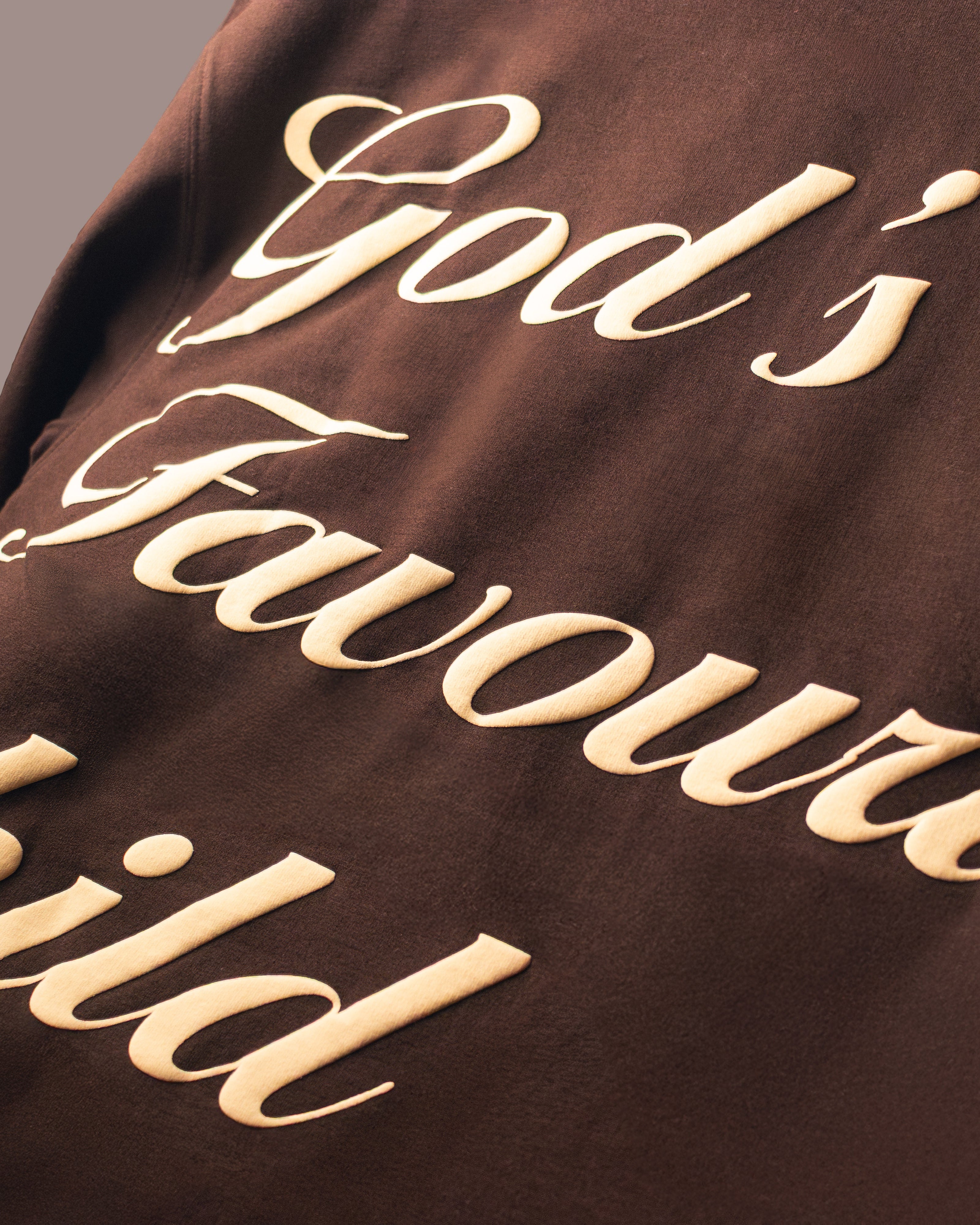 Brown garment with 'God's Favourite Child' text in beige.