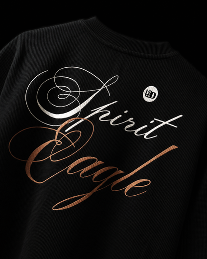Close-up of a black waffle t-shirt featuring a graphic that reads 'Spirit Eagle', with a small circular  logo on the upper right back.