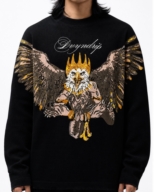 A person wearing a black full-sleeve waffle t-shirt featuring a large graphic print of a crowned eagle (GARUD) with outstretched wings in gold, brown, and white, with the word 'DVYNDRIP' in white script above it.